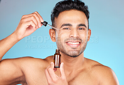 Buy stock photo Skincare, health and portrait of man with serum on face for anti aging and glowing skin on blue background. Beauty, facial and male model with smile and collagen oil product in pipette for treatment.