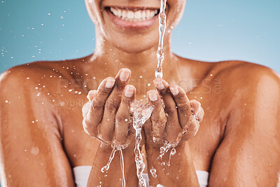 Buy stock photo Water splash, hands and black woman with wellness, skincare and smile. Wet, liquid drops and young female with body care, health and on blue studio background for natural beauty, smooth or clear skin
