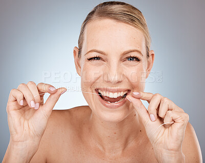 Flossing, dental care and woman cleaning teeth, health smile and wellness against a grey studio background. Breath, mouth and portrait of a model with product for grooming, hygiene and care of tooth