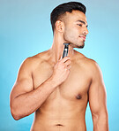 Studio, hair removal or model shaving beard or grooming his face for beauty or facial skincare wellness. Relaxing, blue background or healthy man cleaning his face with electric blade machine 