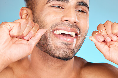 Buy stock photo Face, dental and man floss teeth in studio isolated on blue background. Veneers, invisalign and male model from Brazil flossing, cleaning for wellness or mouth hygiene, oral care and tooth health.