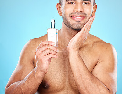 Buy stock photo Cologne, grooming and face of a man for skincare, beauty wellness and luxury cosmetics against a blue background in studio. Self care, smile and portrait of a model with facial perfume product