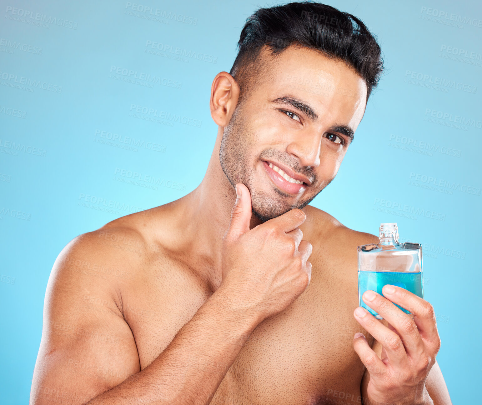 Buy stock photo Beauty, cosmetics and man with cologne in studio on blue background for wellness, self care and luxury. Skincare, grooming and Indian male model with perfume, fragrance and scent in bottle