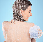Back, shower and woman with loofah, wellness and water for natural beauty, health and against blue studio background. Young female, healthy lady and washing for skincare, liquid drops and relax.