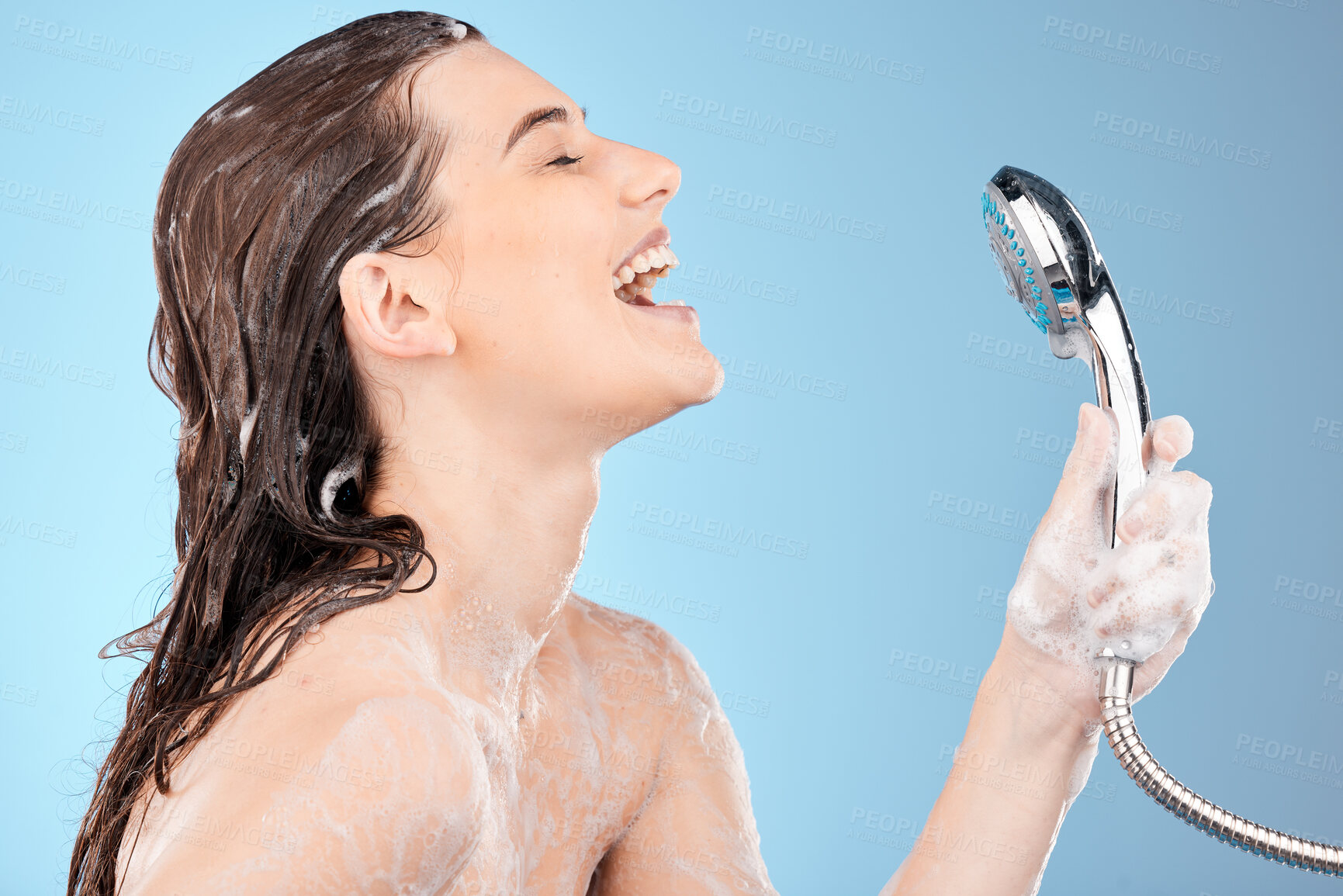 Buy stock photo Woman singing in shower, beauty and shower head with hygiene and hair care, cleaning body and girl profile for washing. Skincare, soap foam and happy with wellness and grooming with blue background.