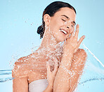 Woman, face skincare or water splash on blue background in studio for dermatology hydration, healthcare wellness or hygiene maintenance. Smile, happy or beauty model with wet motion in house bathroom