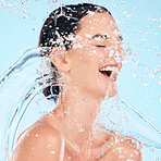 Skincare, facial and woman with water, beauty and splash in shower for cleaning, wellness and relax on blue background. Face, water splash and girl, happy and relax in studio, hydration and aesthetic