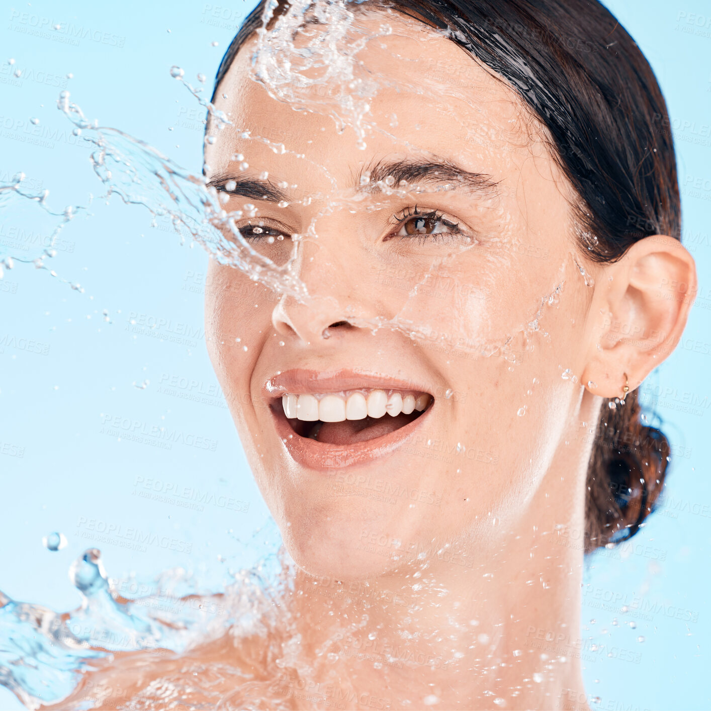 Buy stock photo Face, woman and water for skincare, natural beauty and organic facial against blue studio background. Young female, girl and liquid drops for hygiene, detox and wet for washing, shower and smile.