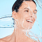 Water splash, happy or woman in shower cleaning her face or body in self care grooming morning routine. Blue background, skincare or healthy model smiles washing for beauty or wellness in studio