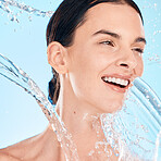 Woman, face and water splash for skincare cosmetics or beauty wellness for happiness in studio. Relax wellness cleaning, happy model and luxury shower for morning dermatology in blue background