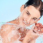 Portrait, shower and pomegranate with a model woman in studio on a blue background for healthcare, hygiene or hydration. Water, splash and fruit with a female posing to promote natural skincare