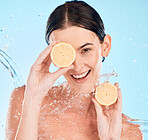 Water splash, lemon and portrait of woman in studio for an organic, natural and healthy skincare treatment. Vitamin c, beauty and model with citrus fruit for face and skin wellness by blue background