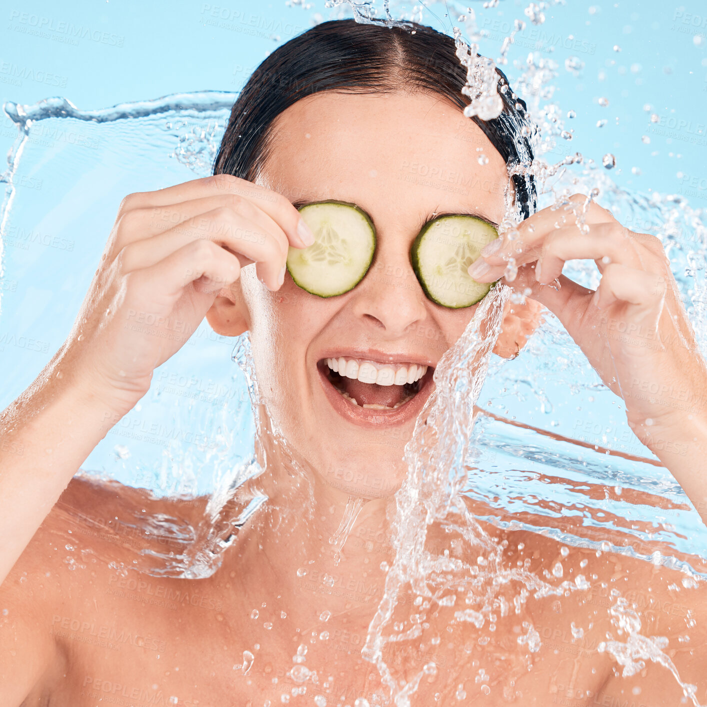 Buy stock photo Water, beauty and cucumber with a woman in the shower in studio on a blue background for hygiene or hydration. Health, wellness and luxury with an attractive young female in the bathroom for skincare