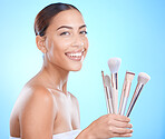 Skincare, beauty and makeup brush for portrait, cosmetics and foundation for glow, smile and happiness on face with blue studio background. Aesthetic Colombia model with beautician or makeover tools