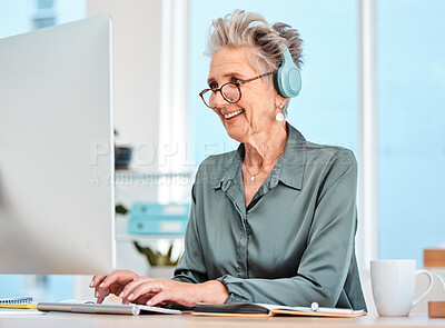 Buy stock photo Elderly woman, computer and smile for typing, listening to music or enjoying work at the office. Senior female employee smiling with glasses and working on desktop PC with headphones at the workplace