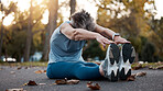 Senior woman, stretching and exercise on asphalt road for fitness, workout and touching feet with lens flare and autumn leaves at nature park. Female on group for warm up and cardio training outdoor