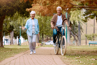 Buy stock photo Senior couple, walking and bike at park, talking and bonding together mock up. Love, retirement and elderly man cycling on bicycle with happy woman speaking outdoors for exercise, health and wellness