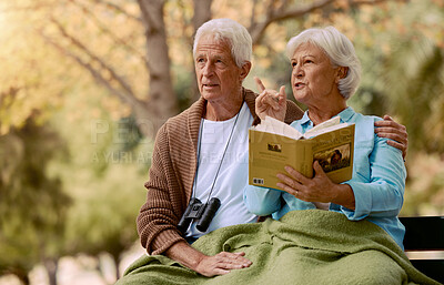 Buy stock photo Birdwatching, book and binoculars with a senior couple sitting on a park bench together in nature. Forest, love and retirement with a mature man and woman in a garden to relax with a summer view