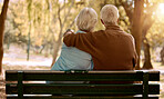Love, hug and old couple in a park on a bench for a calm, peaceful or romantic summer marriage anniversary date. Nature, romance or back view of old woman and elderly partner in a relaxing embrace