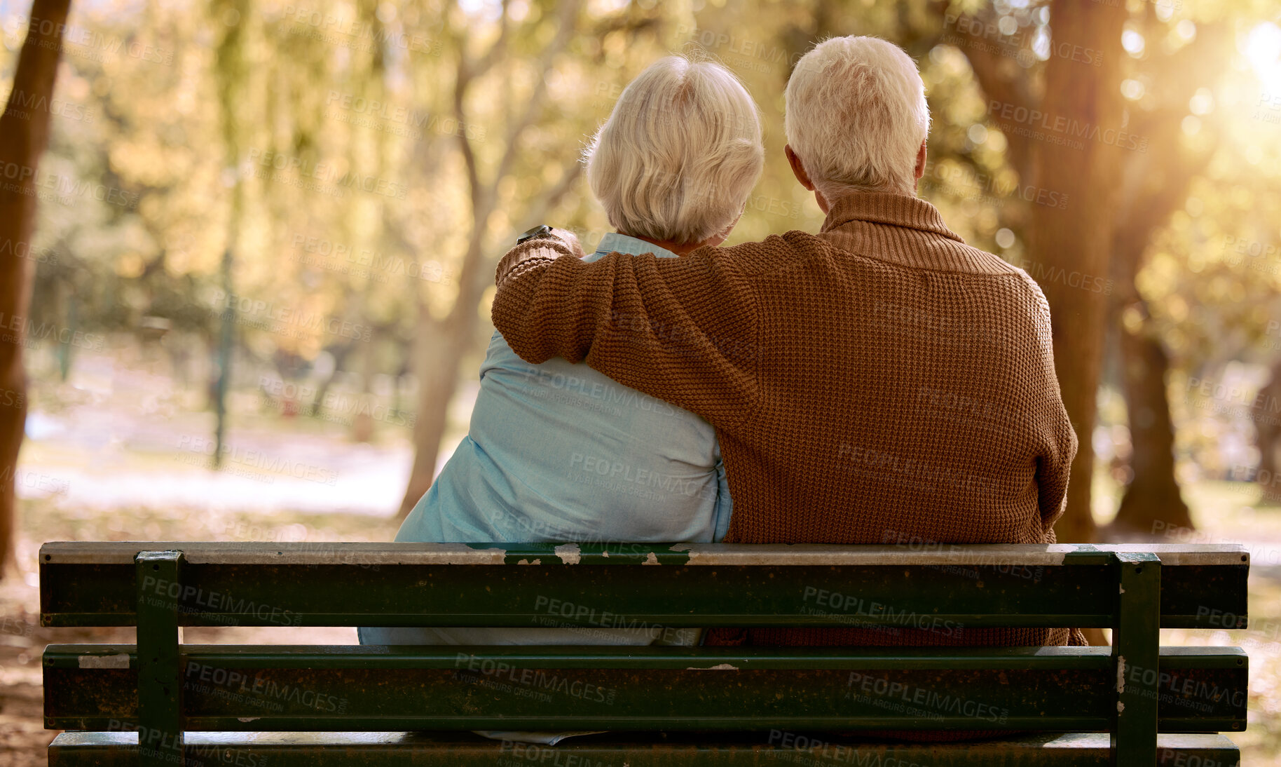 Buy stock photo Love, hug and old couple in a park on a bench for a calm, peaceful or romantic summer marriage anniversary date. Nature, romance or back view of old woman and elderly partner in a relaxing embrace