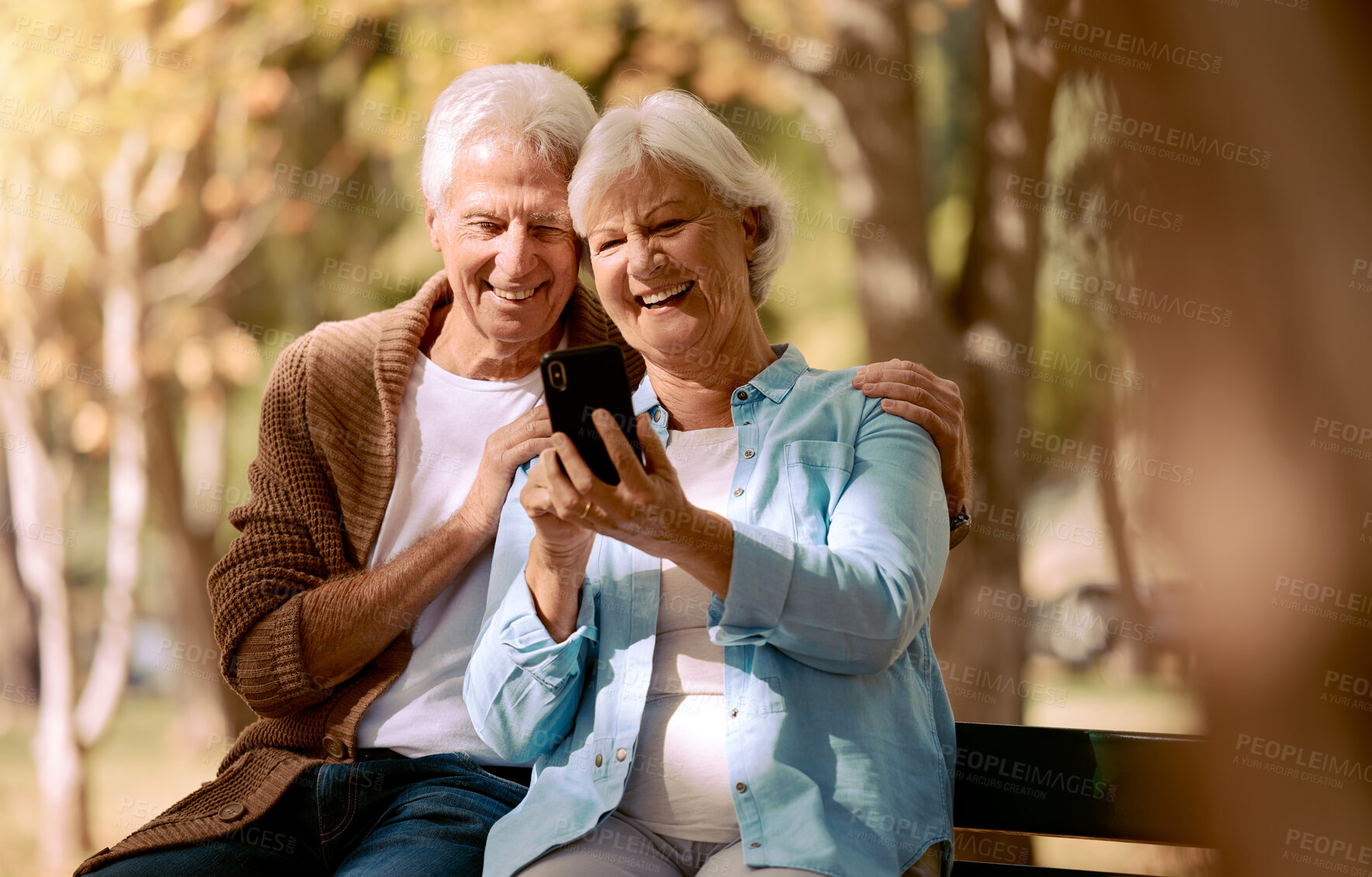 Buy stock photo Relax, happy and phone with old couple in park for video call, social media and communication. Smile, health and internet with man and woman on bench in nature for retirement, 5g and technology