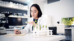 Scientist, plant and medical research with ecology, green leave and nature medicine while writing notes in laboratory. Asian woman doctor with science disk for innovation, development and innovation