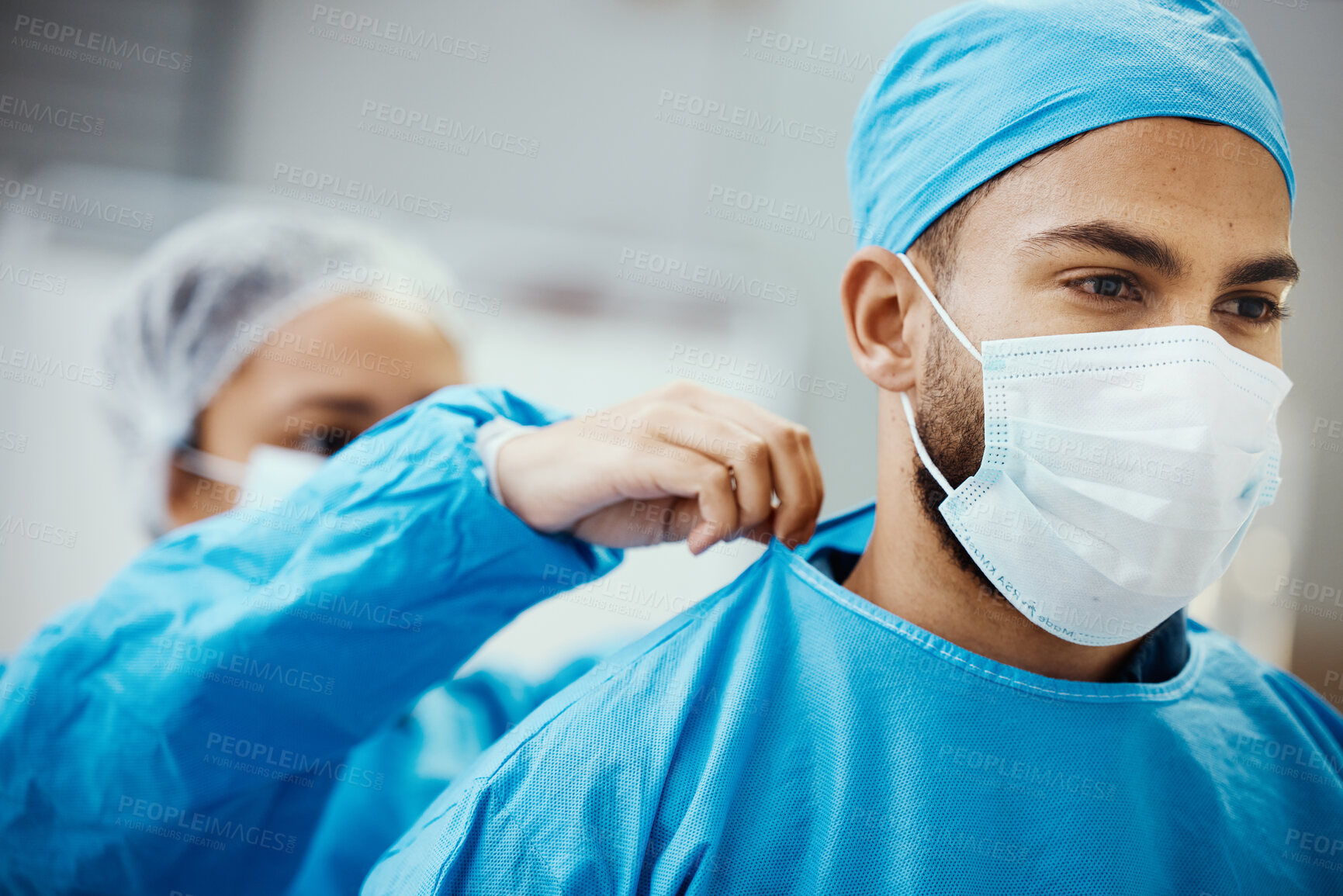 Buy stock photo Surgeon, doctor or medical man with nurse helping with clean scrubs and face mask for surgery, healthcare and safety in theatre. Emergency, ppe and operation staff in a hospital for life insurance