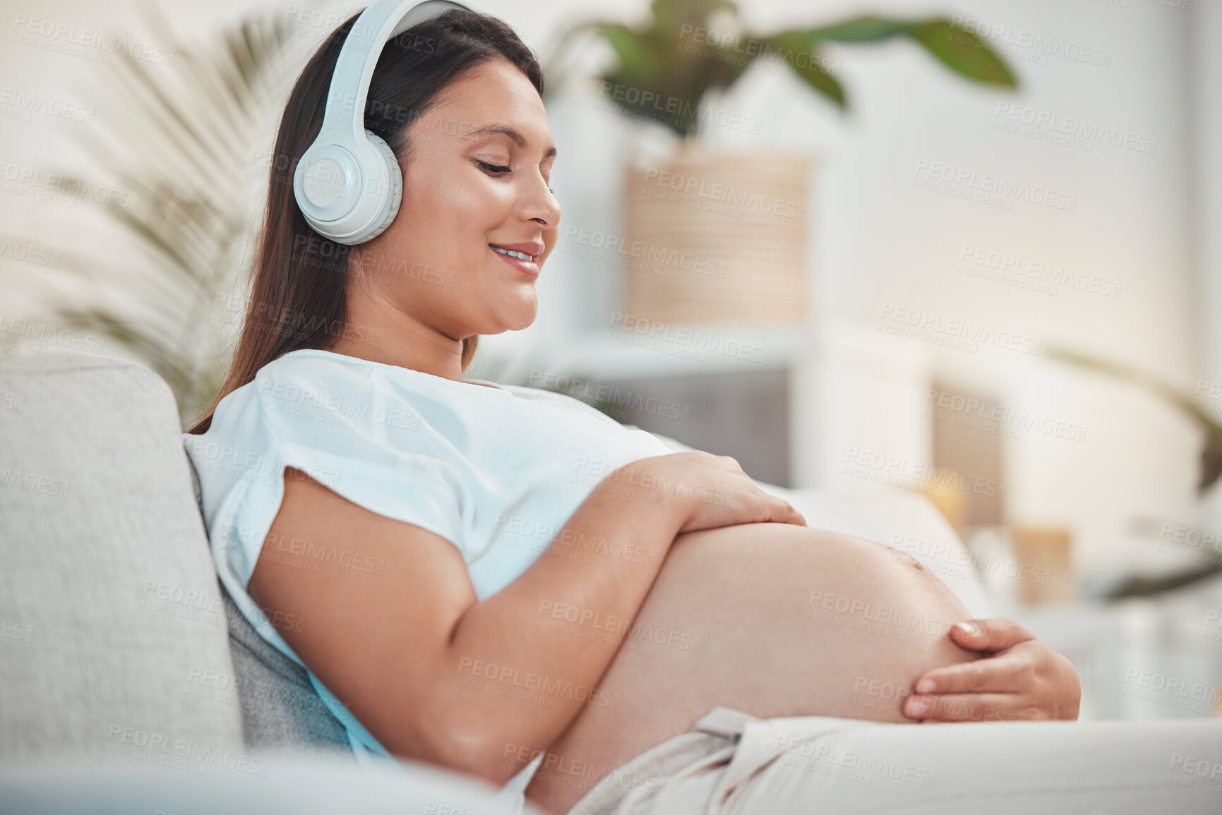 Buy stock photo Pregnant woman, music and holding belly or bump while relaxing and bonding with her baby at home. Babies, mother touching stomach and listen to audio on headset for bond in family home