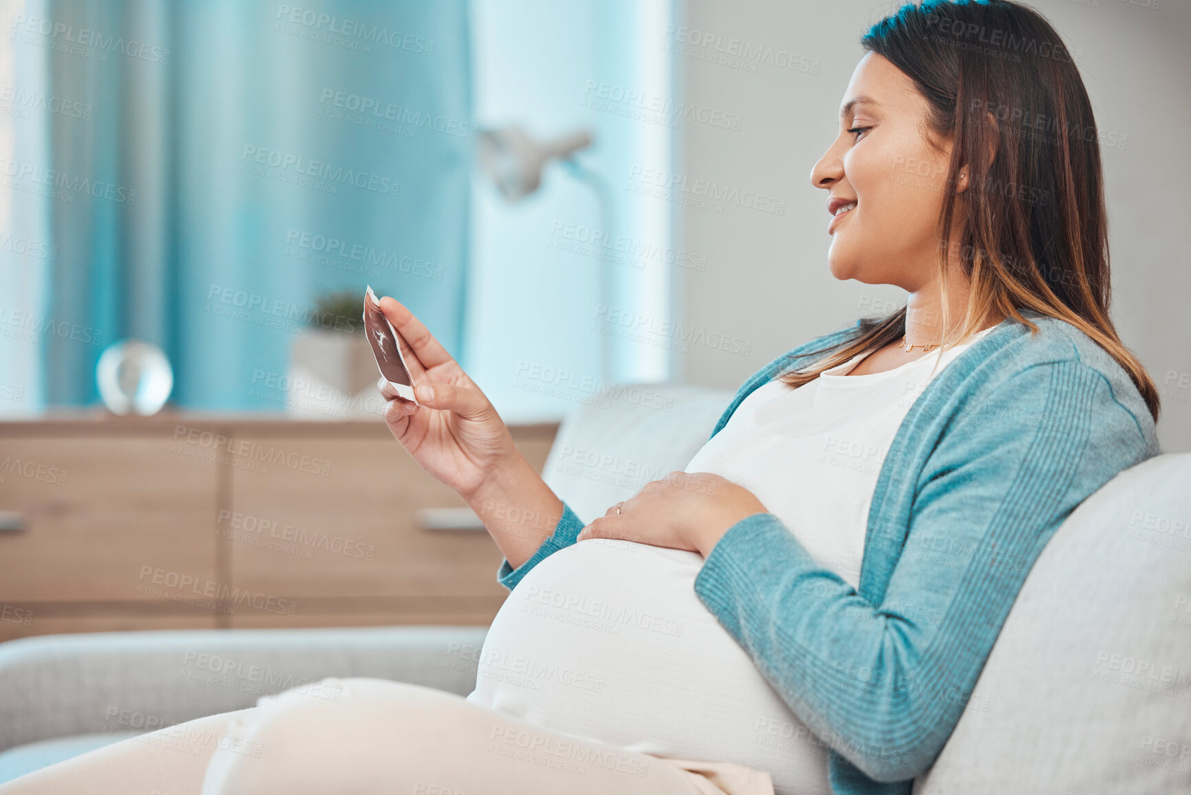 Buy stock photo Pregnant, ultrasound and woman sitting on a sofa in the living room of her home with a baby bump or belly. Mother, pregnancy and photograph with a female parent in her house to relax alone