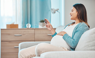 Buy stock photo Pregnant, ultrasound and baby with a mother in the living room, sitting on a sofa in her home alone. Happy, smile and pregnancy with a woman looking a photograph of her infant in the house lounge