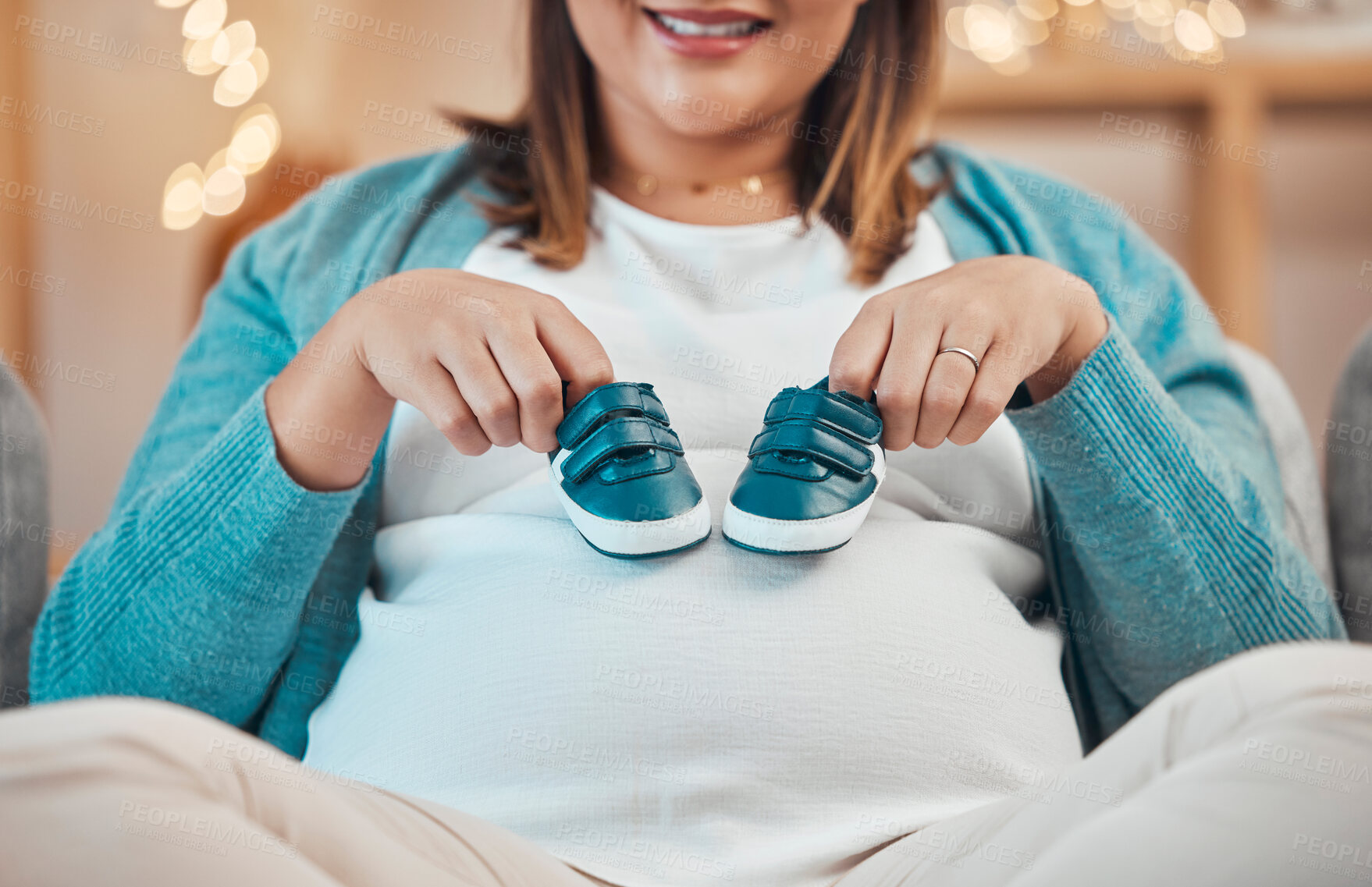 Buy stock photo Pregnant mother, baby shoes and stomach while relax on sofa, happy smile and excited for childbirth in home. Woman, pregnancy and pregnancy with pregnant woman, maternity and motherhood in house