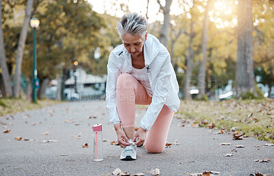 Buy stock photo Fitness, park and senior woman getting ready for running, exercise or outdoor workout with water bottle for fashion, gear and wellness. Nature road with elderly runner or old woman shoes or sneakers