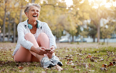 Buy stock photo Health, nature and senior woman in park with phone and headphones to relax during fitness workout. Music, happiness and old lady laughing, sitting on ground in garden after running exercise in autumn