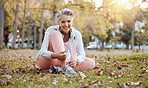 Fitness, shoes and old woman in park for workout, cardio training or morning running. Happy senior female, fitness and tie sneakers on grass lawn to start exercise, healthy lifestyle or body wellness