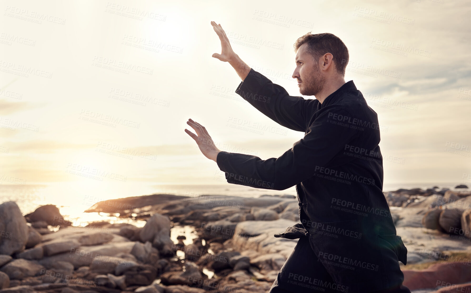 Buy stock photo Nature, zen and tai chi, man on beach for balance and peace for mental wellness or control of body and mind. Spiritual health, fitness and meditation, energy and self care on rocks at sea in sunset.