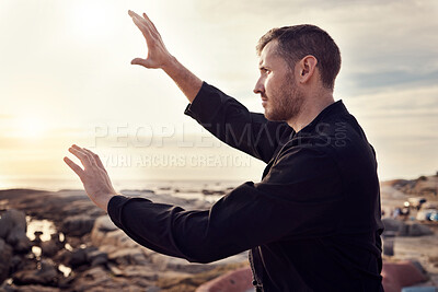 Buy stock photo Tai chi, fitness and martial arts with man at beach for exercise and karate, self defense and zen with peace outdoor profile. Workout on rocks, energy balance and nature, wellness and calm sunrise.