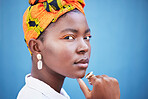 African, fashion and portrait of black woman on blue background with head scarf, glowing skin and makeup. Beauty, glamour and face of female model with exotic style, jewellery and cosmetics in studio