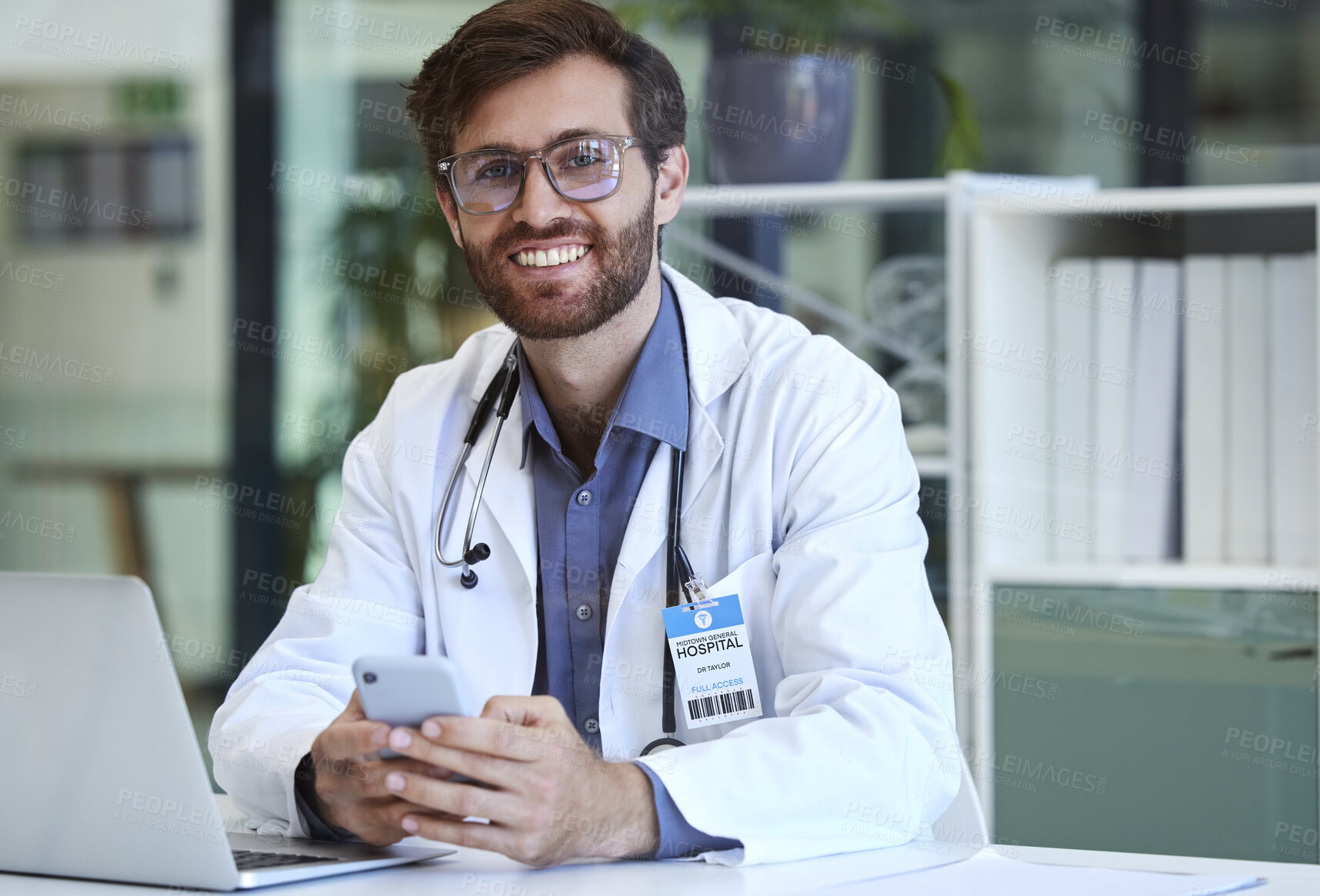 Buy stock photo Doctor, desk and phone with smile for texting, communication or chatting and good connection at hospital. Happy man healthcare or medical professional smiling for telecommunication service at clinic