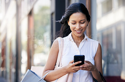 Buy stock photo Woman, smartphone and shopping bag in city, connect and purchase expensive product. Young Hispanic female, girl and consumer typing on phone, boutique item and customer with clothes, sale or discount