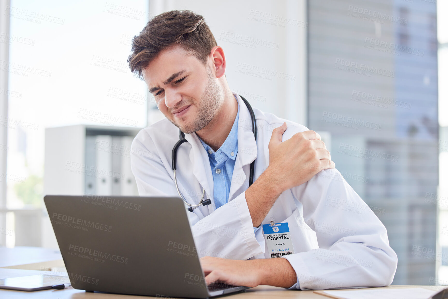 Buy stock photo Laptop, shoulder pain and healthcare with a doctor man at work in his office in the hospital for research. Computer, injury and data with a medicine professional working on innovation in the clinic