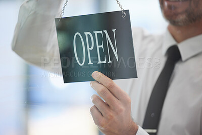 Buy stock photo Businessman, advertising open sign and window in office of new business, company or startup agency. Closeup of executive hanging signage for opening day at glass display, announcement and information