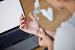 Wrist, pain and woman at laptop working with injury, arthritis or carpal tunnel syndrome concern. Inflammation, uncomfortable and injured girl with medical problem at table with screen mockup.


