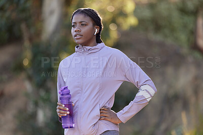 Buy stock photo Exercise, water bottle and black woman outdoor, fitness and workout for wellness, power or health. Nigerian girl, young female or athlete with liquid, hydration or training in nature, rest or earbuds