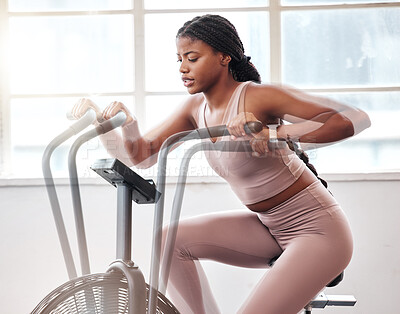 Buy stock photo Motion blur, exercise bike and black woman in gym for workout, cardio training and moving with speed, energy and motivation. Fitness girl, stationary cycling machine and air bike, wellness and action