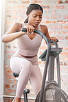 Gym, fitness or black woman on a bike machine in training, cardiovascular exercise or full body workout. Bicycle, energy or African girl athlete cycling for a healthy heart, sports or speed challenge