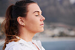 Woman, face and meditation outdoor, calm and spiritual freedom at beach, prayer and breathe in nature. Young female, prayer and eye closed at ocean, balance mindset and zen faith on holiday vacation