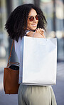 Woman, portrait and luxury shopping, bag and fashion with sunglasses, happy smile and walking in Milan, Italy. Young female, afro and wealthy after retail spending, rich and happiness with wealth 