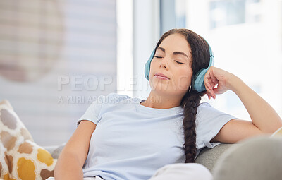 Buy stock photo Headphones, relax and young woman on a sofa listening to calm music, radio or podcast in her living room. Peace, zen and comfortable lady streaming audio, playlist or album on a couch at her home.