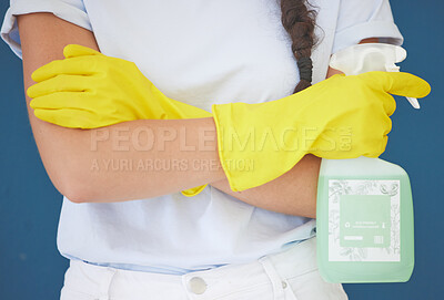 Buy stock photo Cleaning woman and arms crossed with spray product for home hygiene and sanitation routine in blue studio. Housekeeping girl with detergent chemical bottle and safety gloves for spring cleaning.


