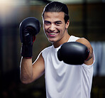 Portrait, fitness and boxing man punching with boxing gloves in a sport gym for health. Athlete, boxer and face of strong male personal trainer prepare for a fight or kickboxing and muay thai event